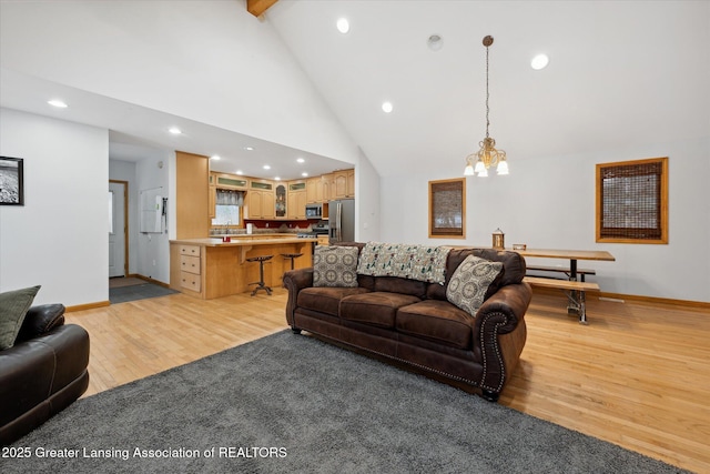 living room with beamed ceiling, a chandelier, high vaulted ceiling, and light hardwood / wood-style flooring