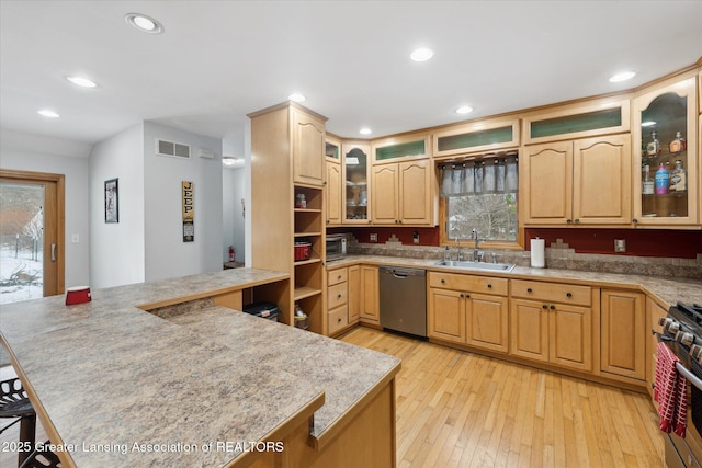 kitchen featuring sink, dishwashing machine, light brown cabinets, light hardwood / wood-style floors, and stainless steel range with gas stovetop