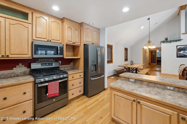 kitchen with light brown cabinetry, decorative light fixtures, lofted ceiling, light hardwood / wood-style floors, and stainless steel appliances