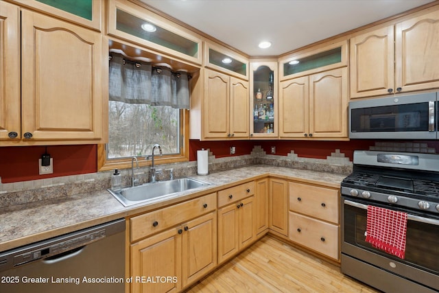 kitchen featuring stainless steel appliances, sink, light brown cabinets, and light hardwood / wood-style flooring