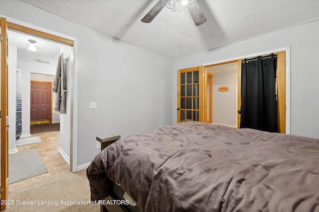 bedroom with ceiling fan, light colored carpet, and a textured ceiling