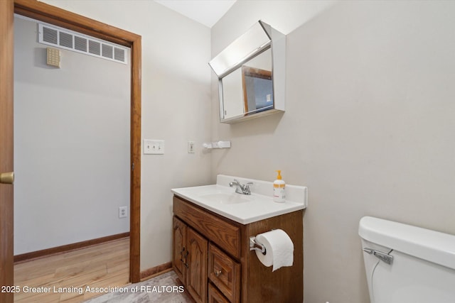 bathroom with hardwood / wood-style flooring, vanity, and toilet