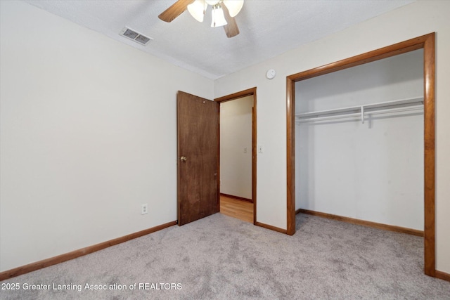 unfurnished bedroom with ceiling fan, light colored carpet, a closet, and a textured ceiling