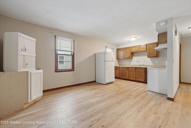 kitchen featuring white refrigerator, range, a textured ceiling, and light wood-type flooring