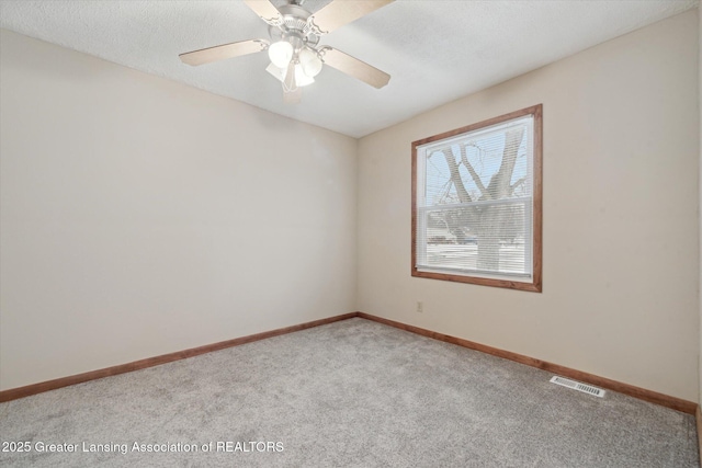 empty room with ceiling fan, light carpet, and a textured ceiling