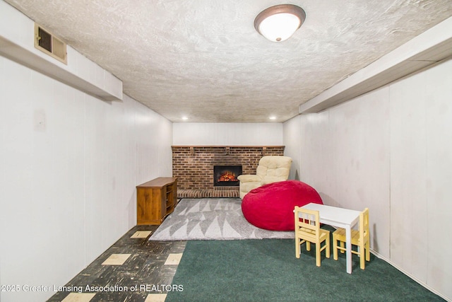 interior space featuring a brick fireplace, dark carpet, and a textured ceiling