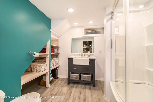 bathroom with hardwood / wood-style flooring, vanity, and combined bath / shower with glass door