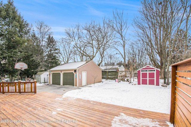 snow covered deck featuring a storage shed and a garage