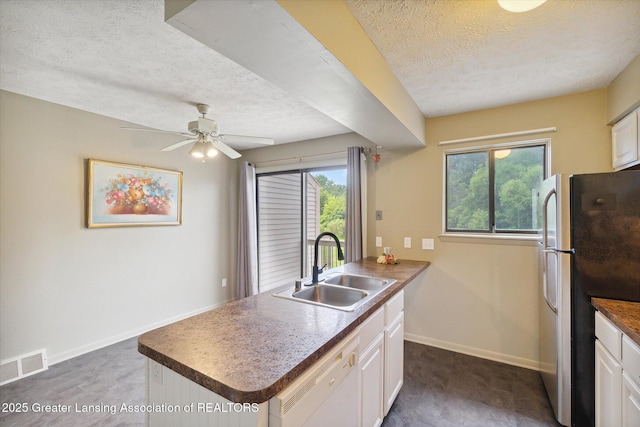 kitchen featuring sink, white cabinetry, a center island with sink, stainless steel refrigerator, and white dishwasher