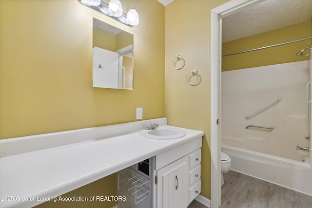 full bathroom with hardwood / wood-style flooring, bathing tub / shower combination, vanity, a textured ceiling, and toilet