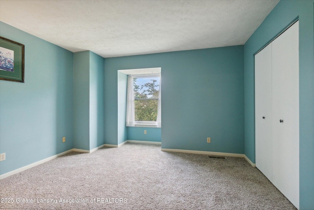 unfurnished bedroom featuring light carpet, a closet, and a textured ceiling