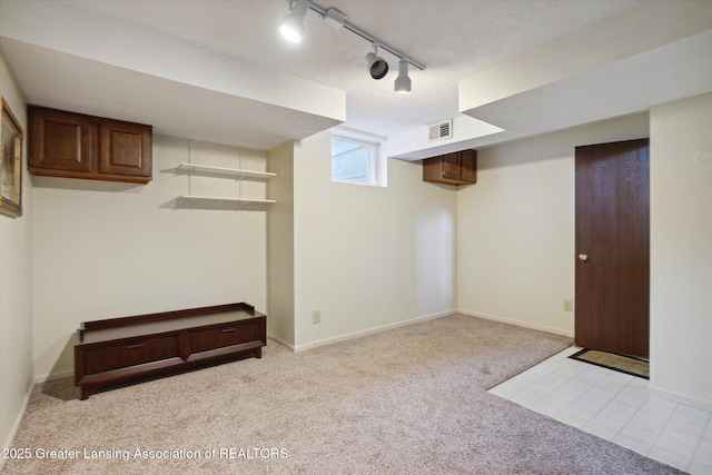 basement with light colored carpet and track lighting