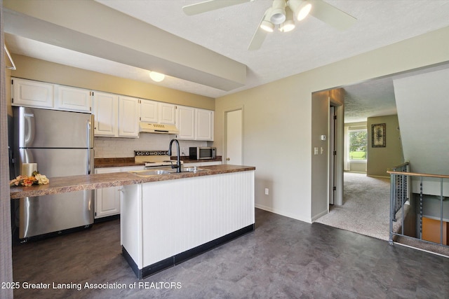 kitchen with appliances with stainless steel finishes, tasteful backsplash, white cabinetry, an island with sink, and a textured ceiling