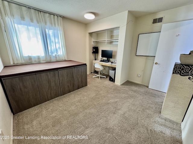 carpeted office featuring a textured ceiling