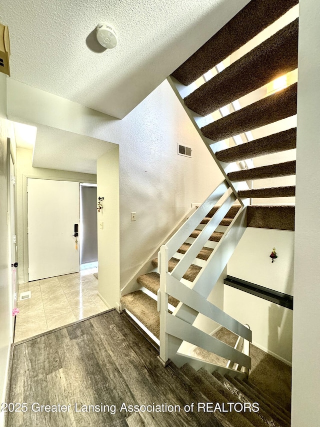 stairway featuring hardwood / wood-style floors and a textured ceiling