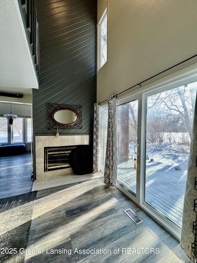 unfurnished living room featuring a high ceiling, a tile fireplace, wood-type flooring, and a textured ceiling