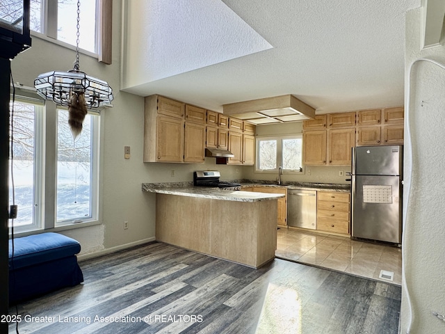 kitchen featuring stainless steel appliances, a textured ceiling, light hardwood / wood-style floors, and kitchen peninsula