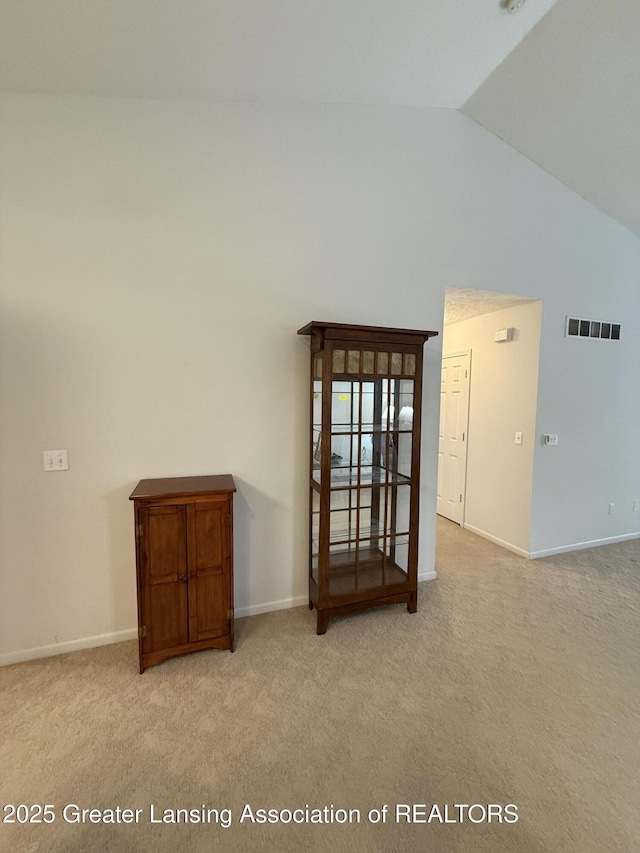 carpeted empty room featuring high vaulted ceiling