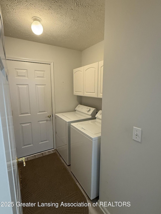 clothes washing area with a textured ceiling, cabinets, and washing machine and clothes dryer