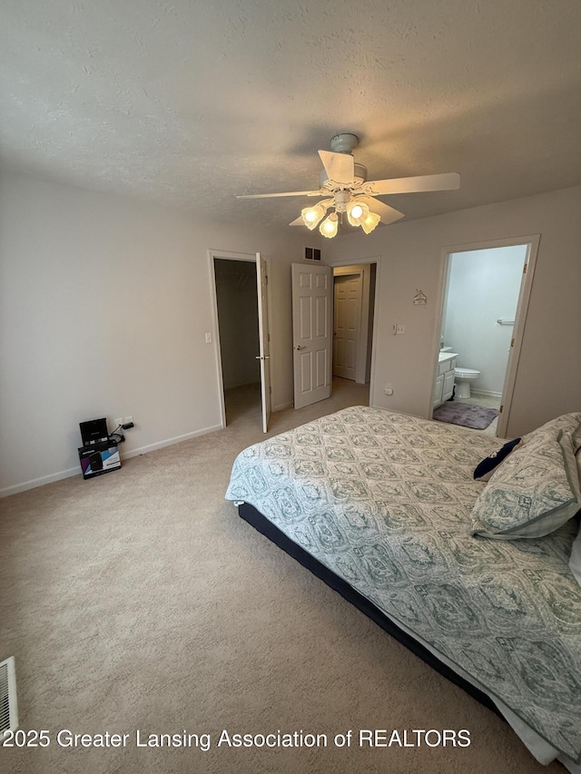 bedroom featuring ensuite bathroom, carpet, ceiling fan, and a textured ceiling