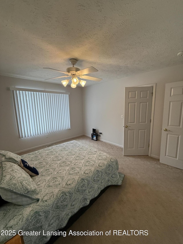 carpeted bedroom with ceiling fan and a textured ceiling