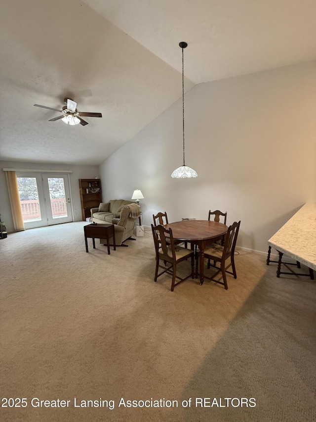 carpeted dining space with ceiling fan and lofted ceiling