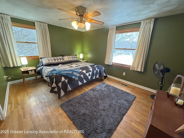 bedroom with ceiling fan, hardwood / wood-style floors, and a textured ceiling