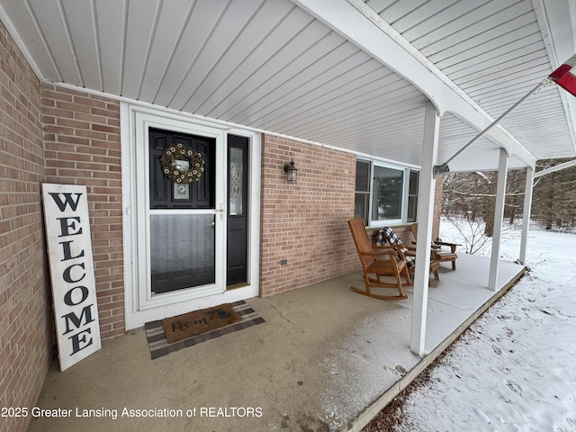 snow covered property entrance with a porch