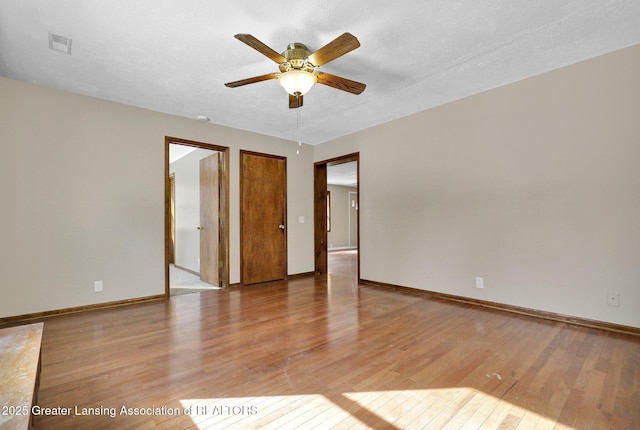 empty room featuring ceiling fan, light hardwood / wood-style flooring, and a textured ceiling