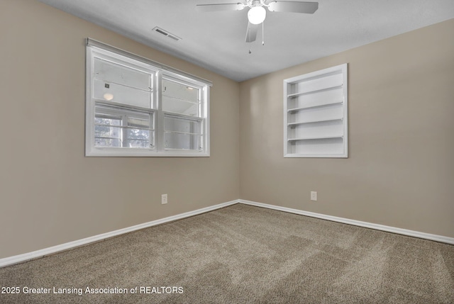 carpeted empty room featuring built in shelves and ceiling fan