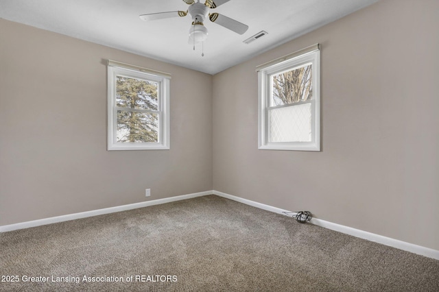 empty room featuring ceiling fan, carpet flooring, and a wealth of natural light