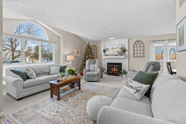 living room featuring light carpet, a wealth of natural light, a large fireplace, and vaulted ceiling