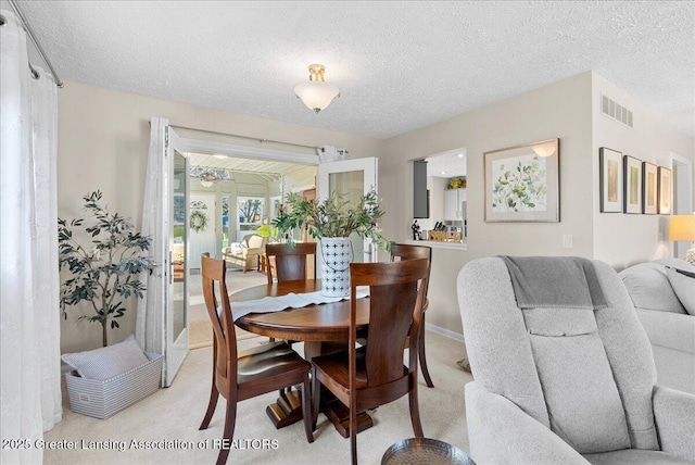 carpeted dining space featuring a textured ceiling