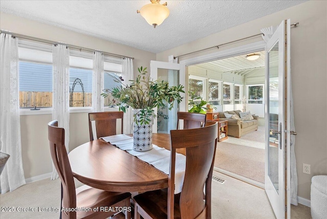 dining room with light carpet and a textured ceiling