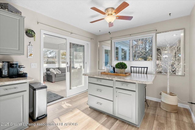 kitchen with light stone counters, a textured ceiling, light hardwood / wood-style floors, and ceiling fan