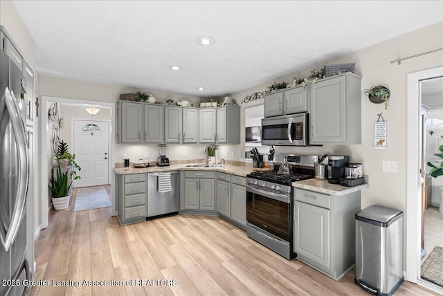 kitchen featuring gray cabinets, appliances with stainless steel finishes, sink, and light wood-type flooring