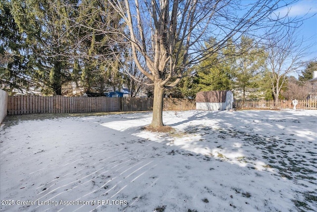 yard covered in snow featuring a storage shed