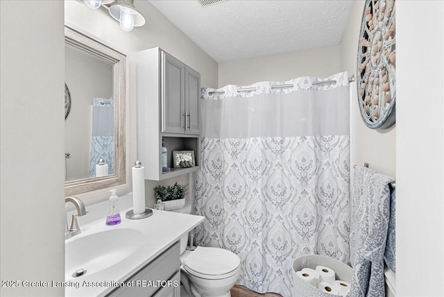 bathroom with vanity, toilet, and a textured ceiling