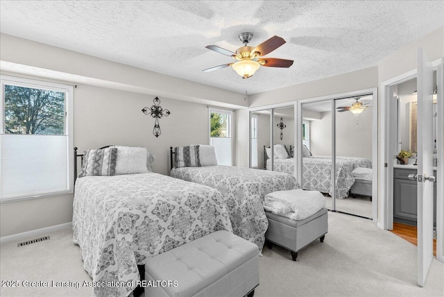 carpeted bedroom featuring multiple closets, ceiling fan, and a textured ceiling