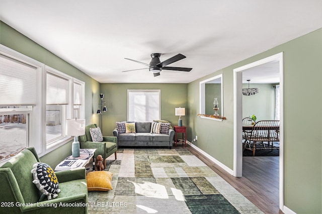 living room featuring a healthy amount of sunlight, ceiling fan with notable chandelier, and wood-type flooring