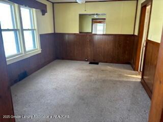 spare room with wooden walls and light colored carpet