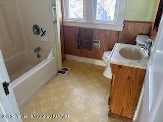 full bathroom featuring vanity, tub / shower combination, toilet, and wood walls