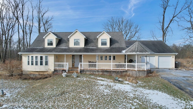 cape cod home featuring a garage and covered porch