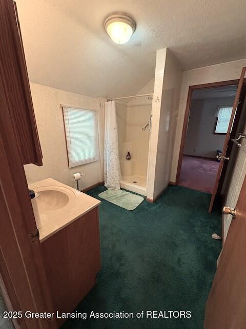 bathroom featuring vanity, a shower with curtain, lofted ceiling, and a textured ceiling