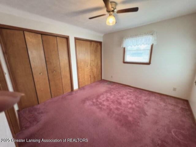 unfurnished bedroom with carpet, two closets, and ceiling fan