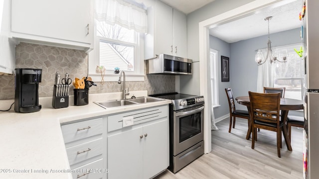 kitchen with decorative light fixtures, tasteful backsplash, sink, white cabinets, and stainless steel appliances