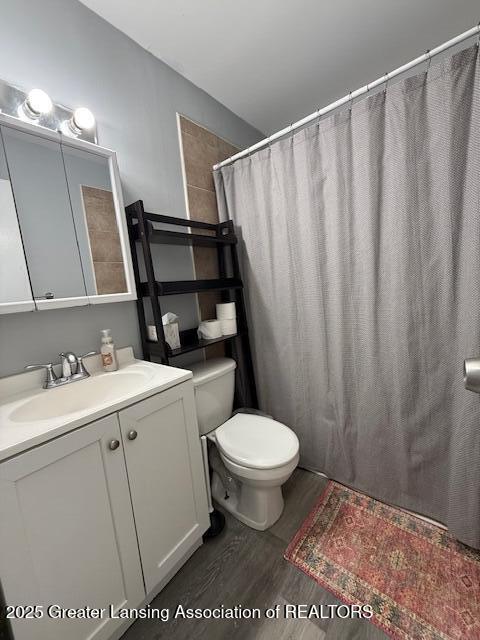 bathroom with a shower with shower curtain, vanity, toilet, and hardwood / wood-style floors