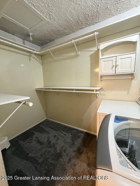 walk in closet with dark carpet and washer / dryer