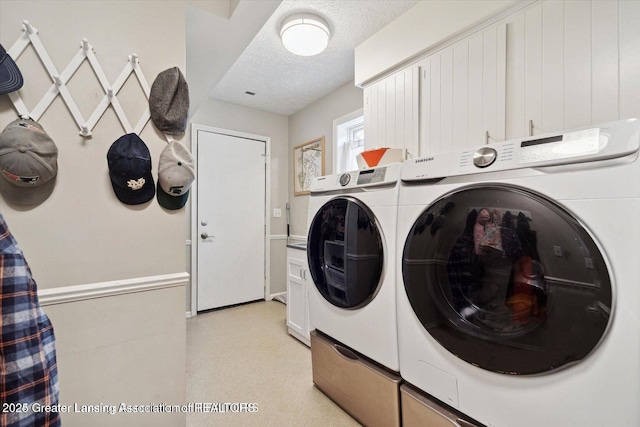 clothes washing area featuring cabinets, washing machine and clothes dryer, and a textured ceiling