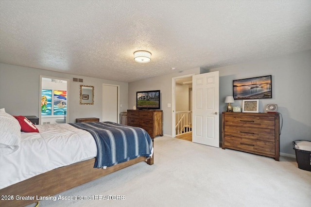 bedroom with light colored carpet and a textured ceiling